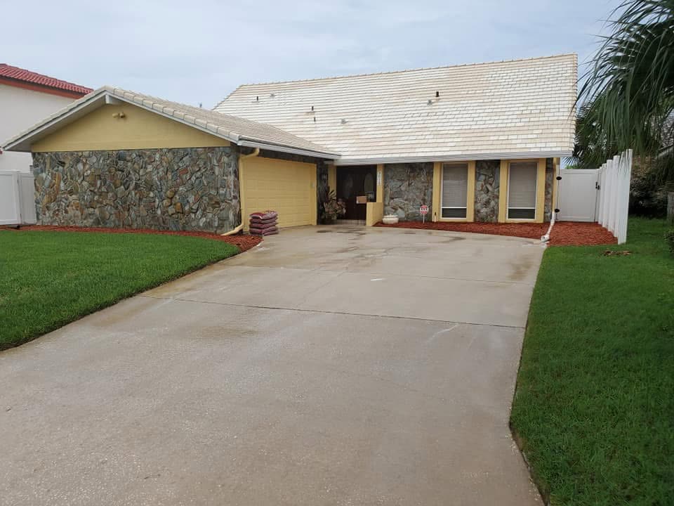 After: The same home with a clean, light tile roof and a washed driveway